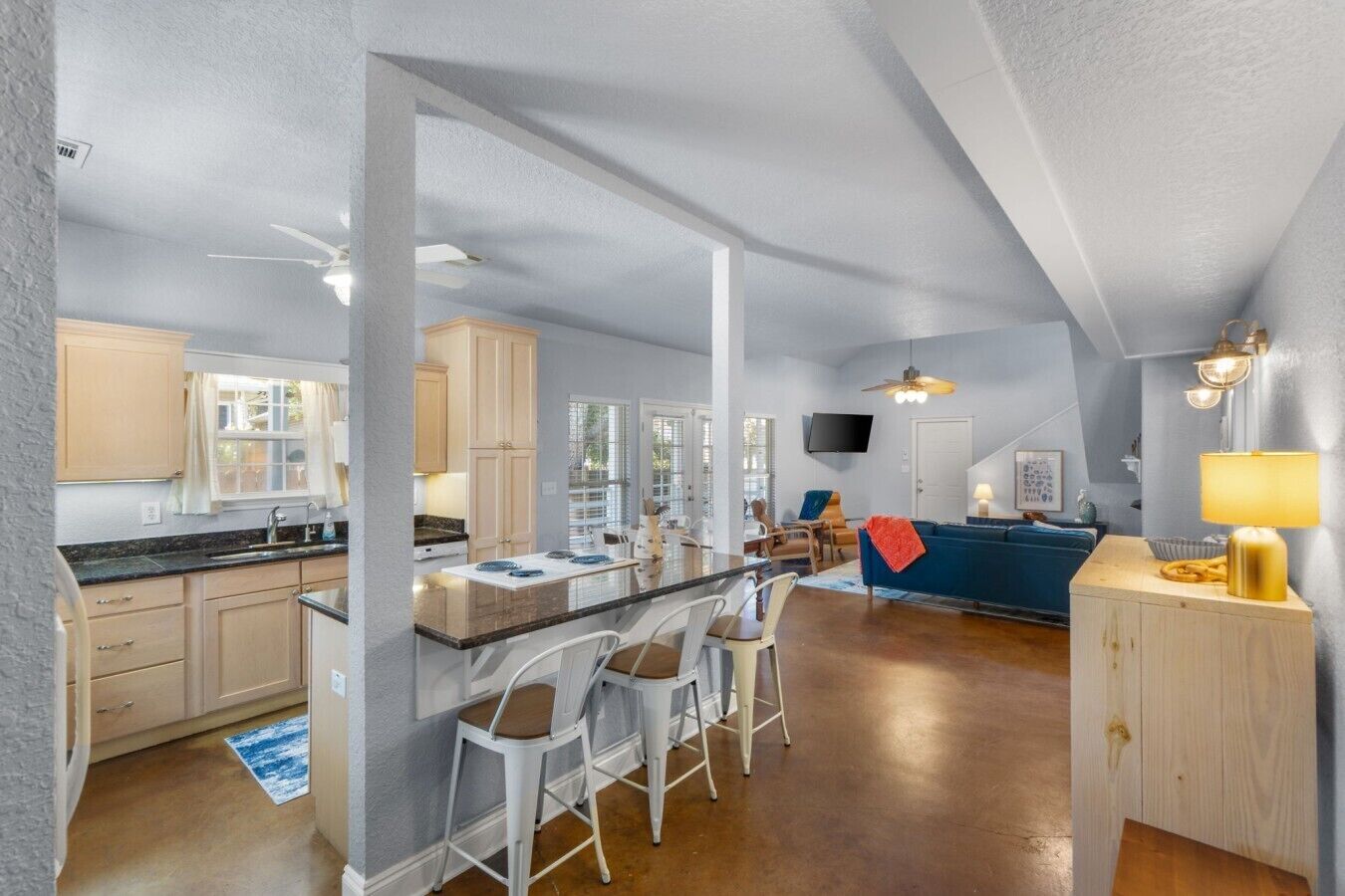 A spacious kitchen with a large island, bar stools, and a dining area with a blue sofa.