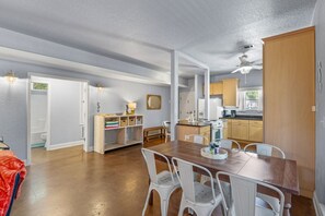 Een ruime keuken met houten kastjes, een eettafel met stoelen, en een klein zithoekje met een bank.