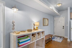 A hallway with a wooden console table, a bench, a wall-mounted mirror, and a door. - 3BR Coastal Retreat | 10 Min to Beaches (Pensacola)