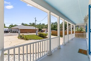 A covered porch with a view of a backyard, a wooden building, and a fenced area. - 3BR Coastal Retreat | 10 Min to Beaches (Pensacola)