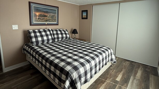 A bedroom with a bed, a framed picture on the wall, a lamp, and a wardrobe. - Peaceful 3-Bedroom home on Lake Oahe (Pierre)