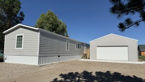 A two-story building with a garage, a covered porch, and a small shed. - Peaceful 3-Bedroom home on Lake Oahe (Pierre)