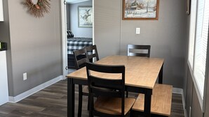 A dining area with a wooden table and chairs, a framed picture on the wall, and a door leading to another room. - Peaceful 3-Bedroom home on Lake Oahe (Pierre)