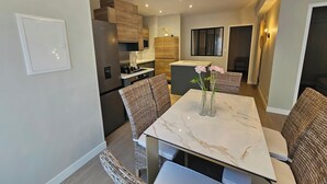 A modern kitchen with built-in appliances and a dining area with wicker chairs and a marble table. - Azure Treasure Chest (La Londe-les-Maures)