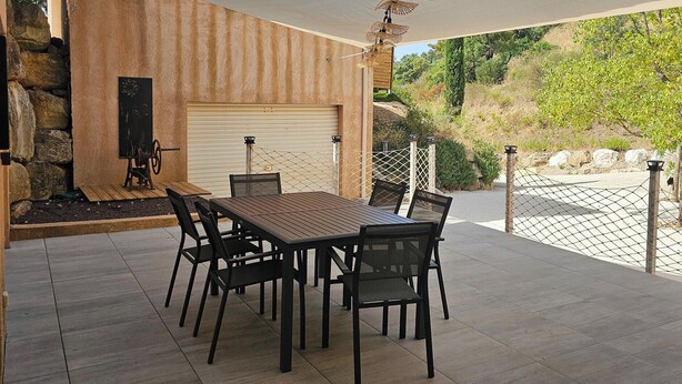 A patio with a table and chairs, a stone wall, and a garage door. - Azure Treasure Chest (La Londe-les-Maures)