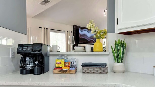 Eine Küche mit Kaffeemaschine, Snacks, einem Fernseher und einer Topfpflanze.