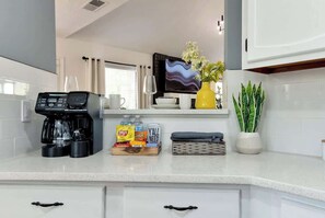 A kitchen with a coffee maker, snacks, a TV, and a potted plant. - Daylilly House/ Family Friendly with Gameroom (Lawrenceville)