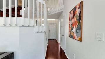 Un pasillo con una escalera, una puerta y un cuadro en la pared.