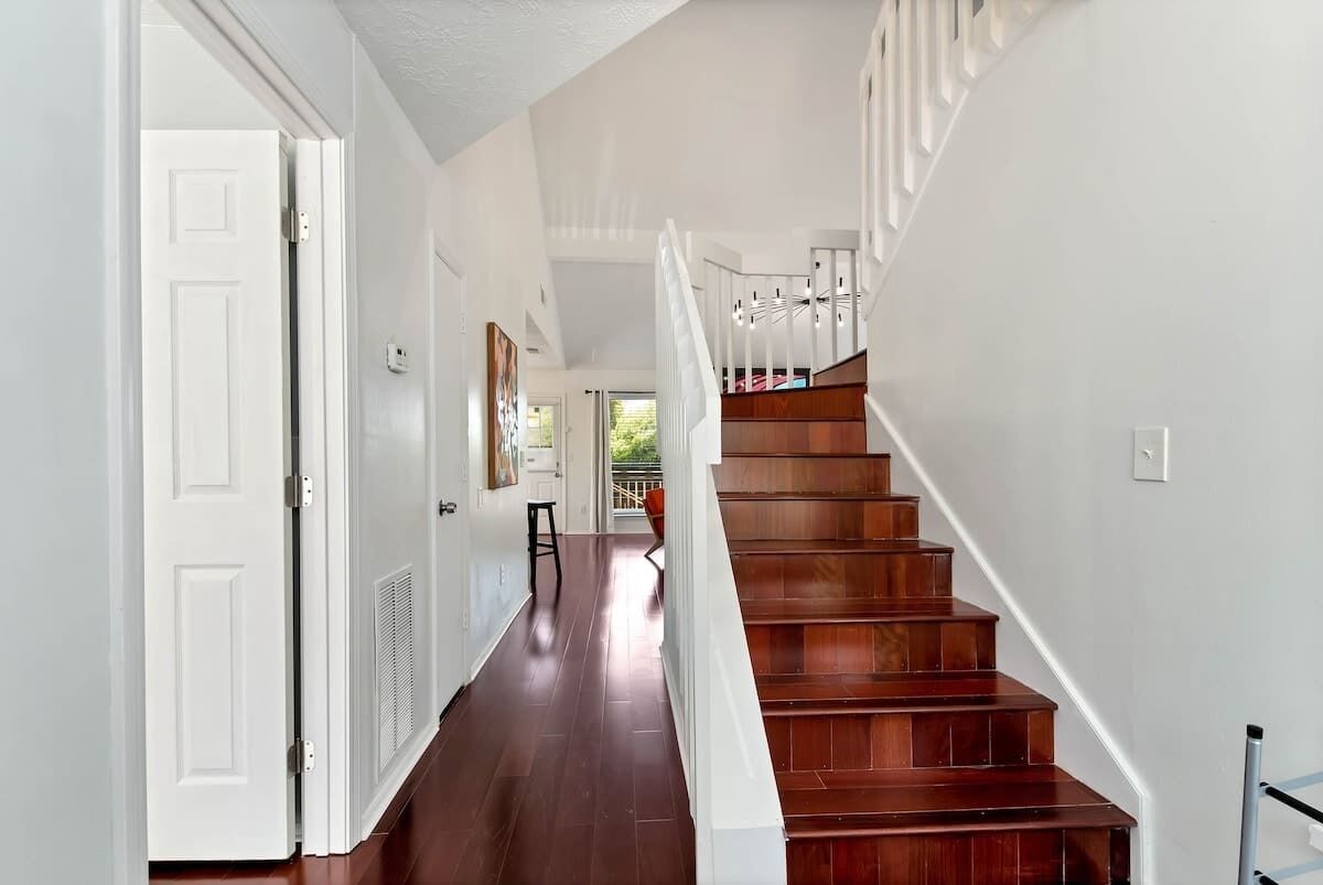 Una escalera con escalones de madera y barandillas blancas, que conduce a un piso superior.