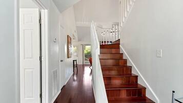 Una escalera con escalones de madera y barandillas blancas, que conduce a un piso superior.