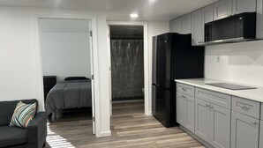 Eine moderne Küche mit grauen Schränken, einem schwarzen Kühlschrank und einer Mikrowelle.
