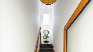 Eine Treppe mit Teppichstufen, Holzhandläufen und einer Tür mit Milchglasfenster.