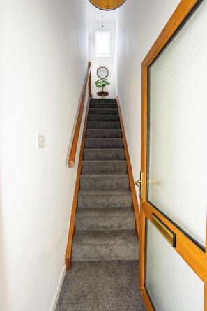 Eine Treppe mit Teppichstufen, Holzhandläufen und einer Tür mit Milchglasfenster.