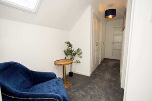 Ein Flur mit einem blauen Sofa, einem kleinen Holztisch mit einer Pflanze und einer Tür am Ende.