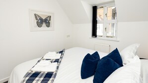 Ein Schlafzimmer mit einem Bett, einem Fenster, einer Heizung und einer Wandleuchte.