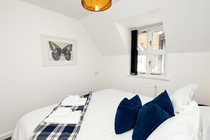 Ein Schlafzimmer mit einem Bett, einem Fenster, einer Heizung und einer Wandleuchte.