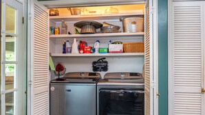 Eine kleine Küche mit Kühlschrank, Herd und Regalen voller Küchenutensilien.