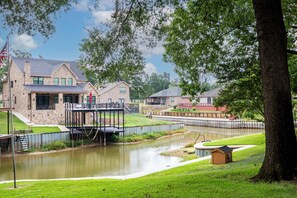 A residential area with stone houses, a small bridge over a pond, and a grassy lawn. - Charming waterfront getaway with great water access. (Tool)