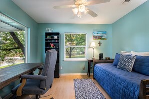 A room with a desk, chair, bed, and a window with a view of trees. - Charming waterfront getaway with great water access. (Tool)