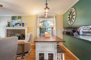 A kitchen with a wooden island, a dining area with a chair, a fireplace, and a wall clock. - Charming waterfront getaway with great water access. (Tool)
