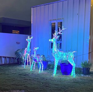 Un bâtiment sur lequel est apposée une pancarte indiquant « DÉFENSE DE PASSER », avec une fenêtre et trois figurines de rennes illuminées.