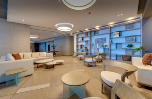 A modern lobby with a sofa, chairs, a coffee table, and a bookshelf. - Beachfront Apartment with the best location and views. Best Experience in Cartagena (Cartagena de Indias)