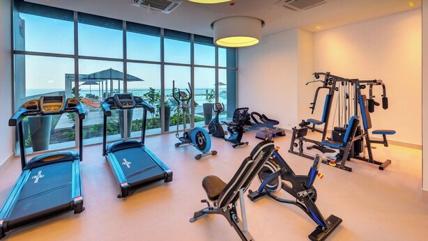 Ein Fitnessstudio mit Laufbändern, Crosstrainern und Gewichtmaschinen, großen Fenstern und Blick ins Freie.