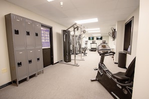 Una palestra con armadietti, attrezzature per esercizi e un tapis roulant.