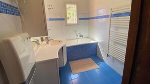 Et badeværelse med badekar, vask og et vindue.