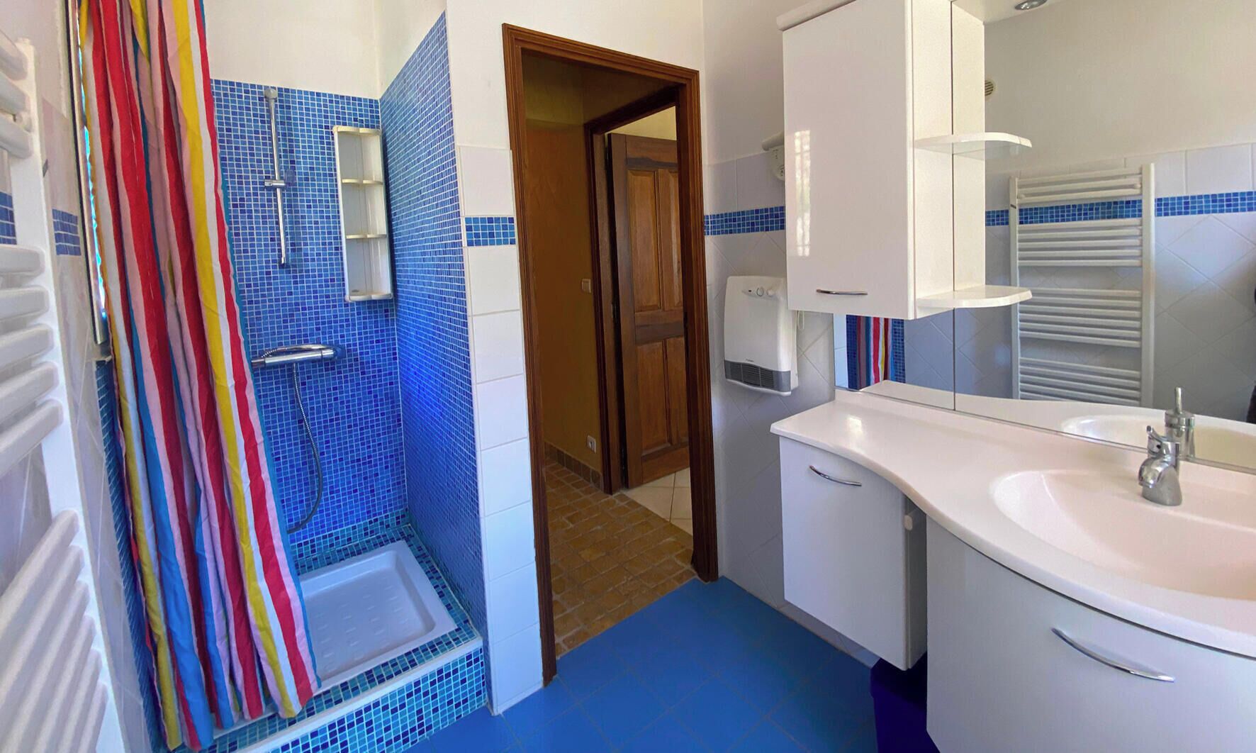 Une salle de bain avec une douche, un lavabo et un miroir.
