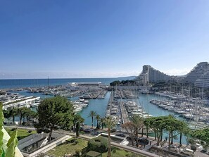 A marina with numerous boats docked, a clear sky, and modern buildings in the background. - Marina 6 Pers ParkingPrivé Vue Mer 7ème Clim WIFI (Villeneuve-Loubet)