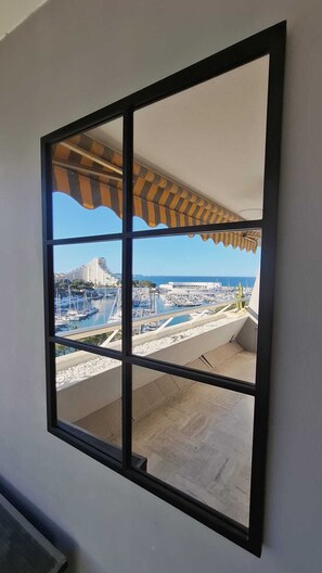 A window with a view of a marina, boats, and buildings. - Marina 6 Pers ParkingPrivé Vue Mer 7ème Clim WIFI (Villeneuve-Loubet)