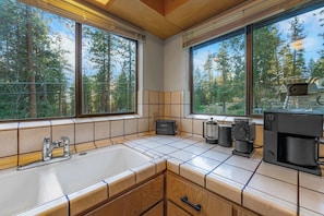 A kitchen with a large window, a sink, a toaster, and a coffee maker. - Granite Heights - Pet Friendly Retreat (Stateline)