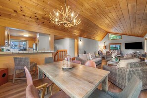 A spacious living area with a wooden ceiling, a dining table, wicker furniture, and a mounted television. - Granite Heights - Pet Friendly Retreat (Stateline)