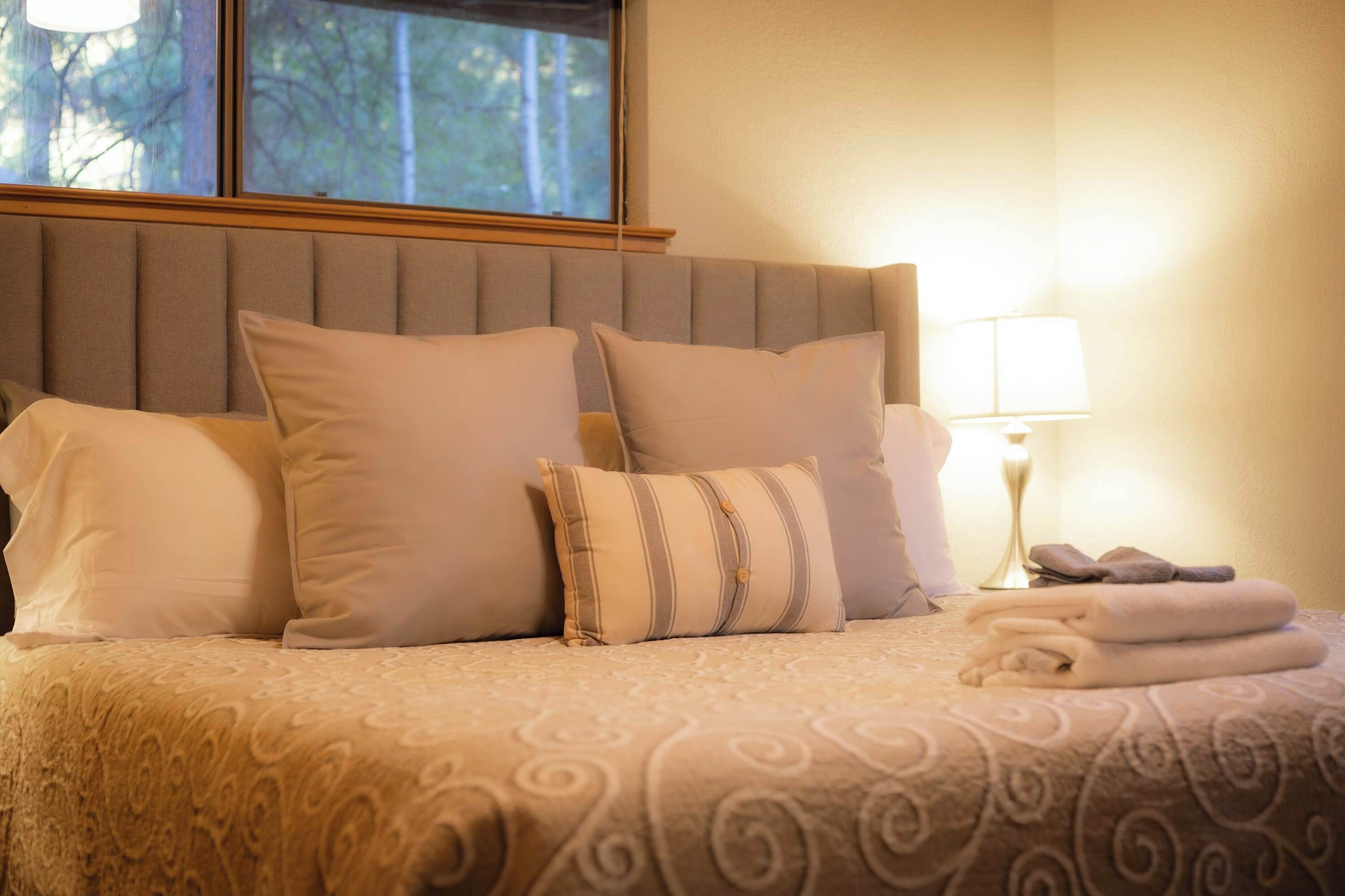 A bed with a patterned bedspread, a headboard, and pillows.