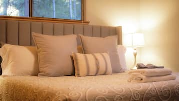 A bed with a patterned bedspread, a headboard, and pillows.