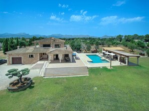 A two-story house with a swimming pool, outdoor seating, and a stone pathway. - Impressive & Spacious Villa - Private Pool, Outdoor Kitchen, Bar & Sauna - 20 mins walk to Alcudia! (Alcudia)