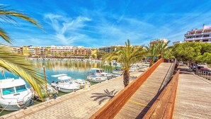 A marina with boats docked, a wooden walkway, and buildings in the background. - Impressive & Spacious Villa - Private Pool, Outdoor Kitchen, Bar & Sauna - 20 mis walk to Alcudia! (Alcudia)