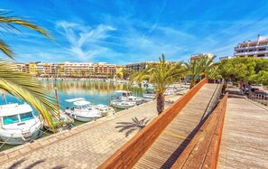 Ein Yachthafen mit vertäuten Booten, einer Holzpromenade und Gebäuden im Hintergrund.