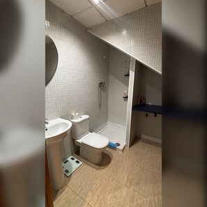 Kylpyhuone, jossa on wc, pesuallas, suihku ja sininen taso.