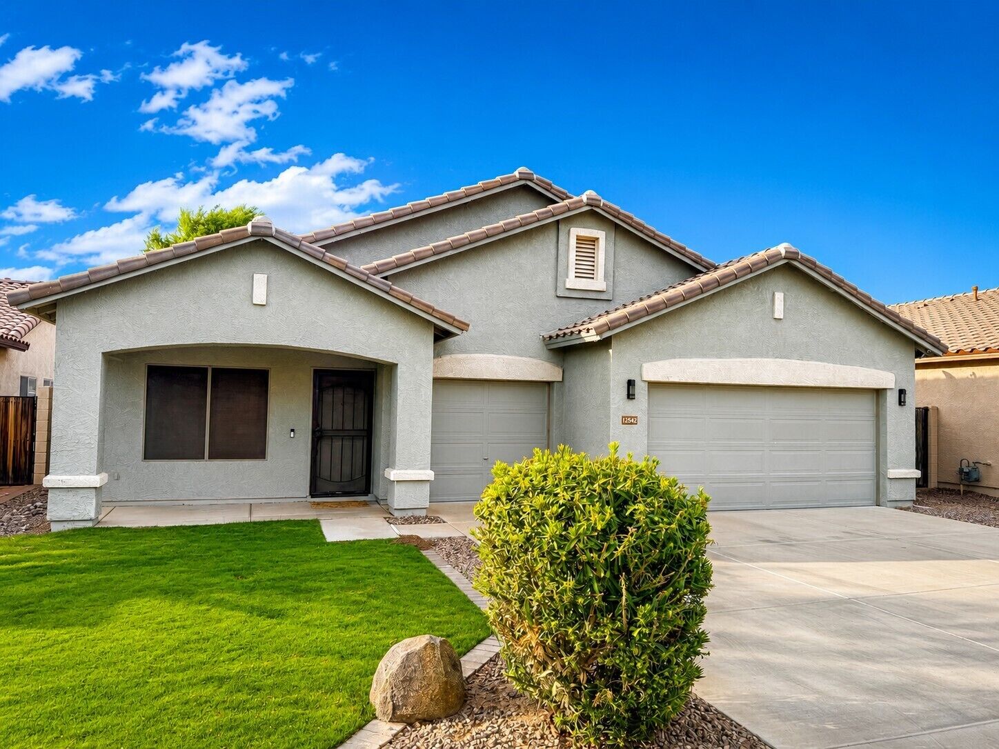 A residential house with a garage, a front door, and a well-maintained lawn.