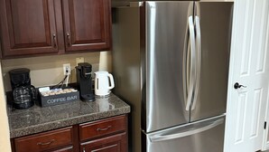 Una cocina con gabinetes de madera oscura, un refrigerador de acero inoxidable, una cafetera y una barra para café.