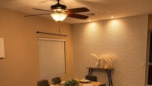 Un comedor con una mesa dispuesta para seis comensales, un ventilador de techo y una pared con textura.