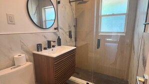 Ein modernes Badezimmer mit Toilette, Waschbecken, Spiegel und Dusche.