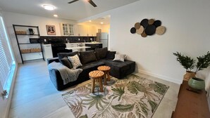 Ein modernes Wohnzimmer mit einer schwarzen Couch, einem Couchtisch und einem Teppich mit Muster.