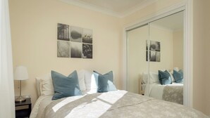 A bedroom with a bed, a nightstand, a lamp, a mirror, and wall art. - Modern Home nr Exeter, Garden & Private Parking (Bradninch)