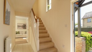 A staircase leading to a living area with a sofa and a painting on the wall. - Modern Home nr Exeter, Garden & Private Parking (Bradninch)