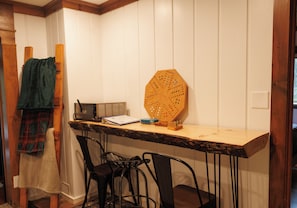 A small, cozy room with a wooden table, two chairs, a wooden pegboard, and a television.