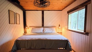 A room with a bed, wooden walls, a window, and a ceiling fan. - Lakefront Cabin Near Duluth (Duluth)