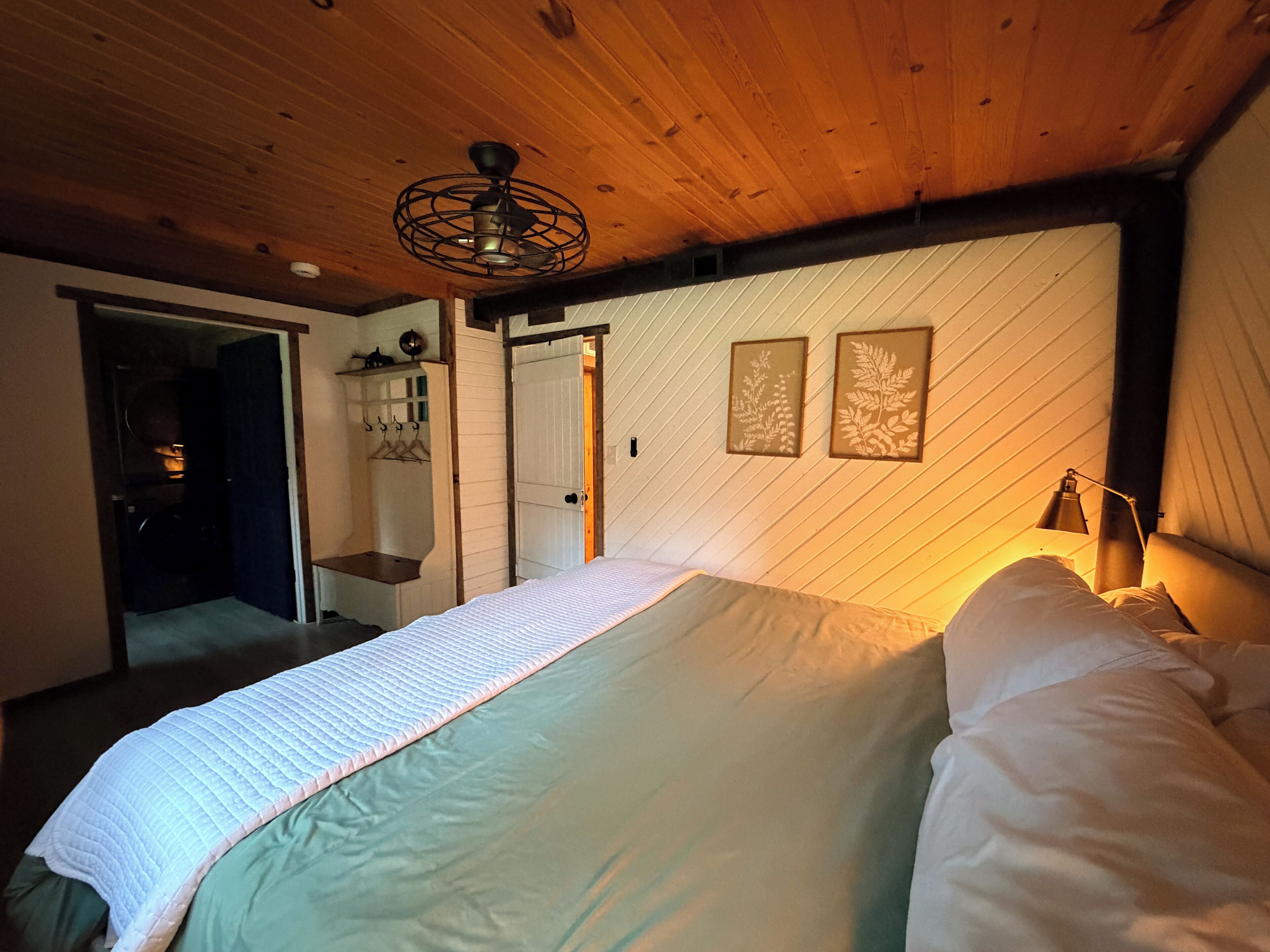 A bedroom with a bed, a wardrobe, a door, and a wall-mounted picture.